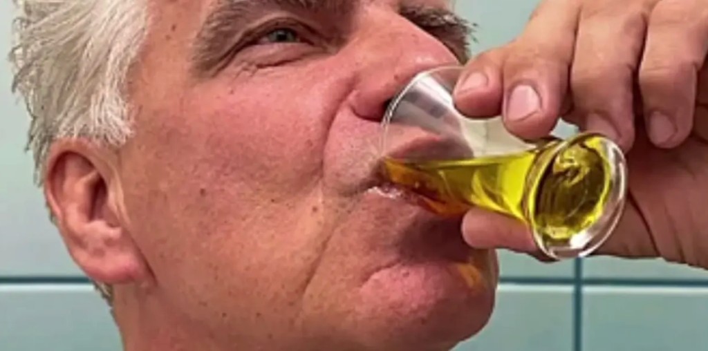 Hombre tomando su batido sustitutivo de un vaso pequeño.